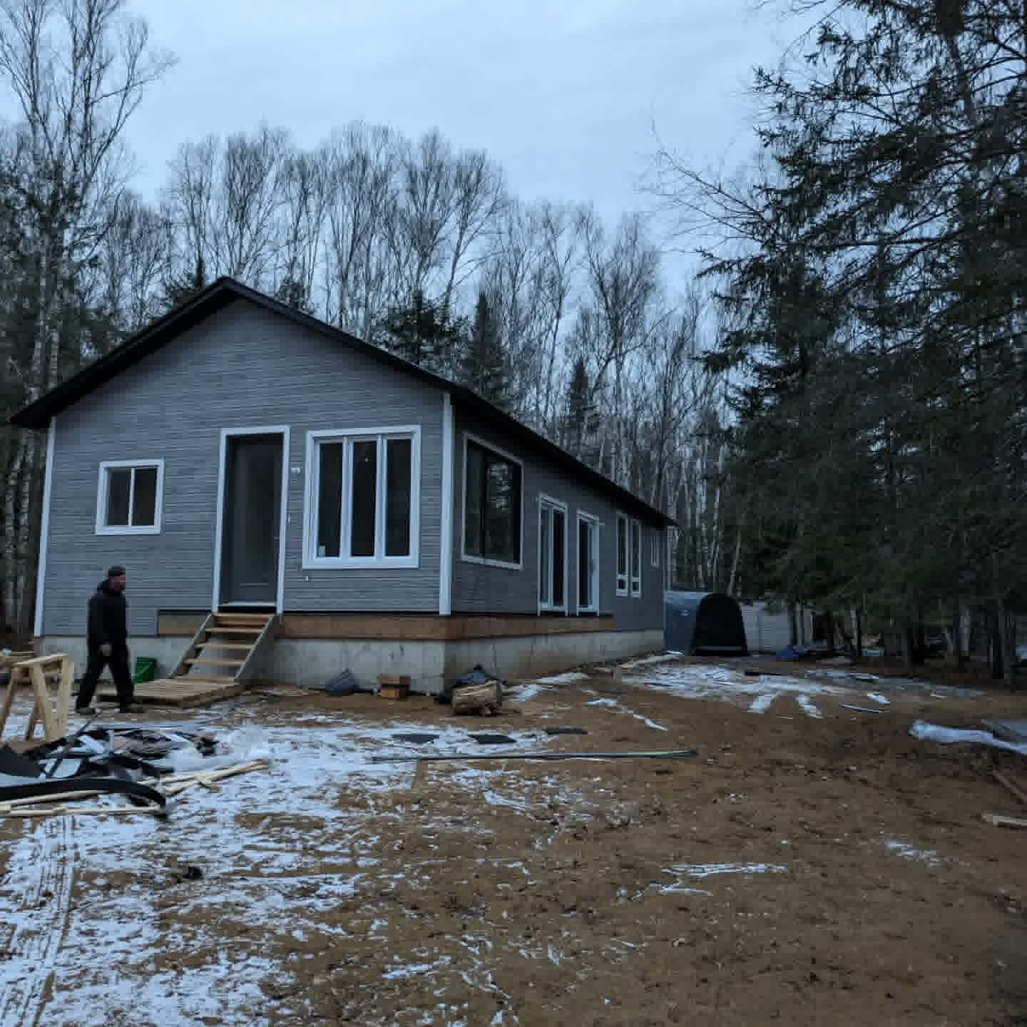 Maison résidentielle avec revêtement extérieur installé sur un terrain boisé
